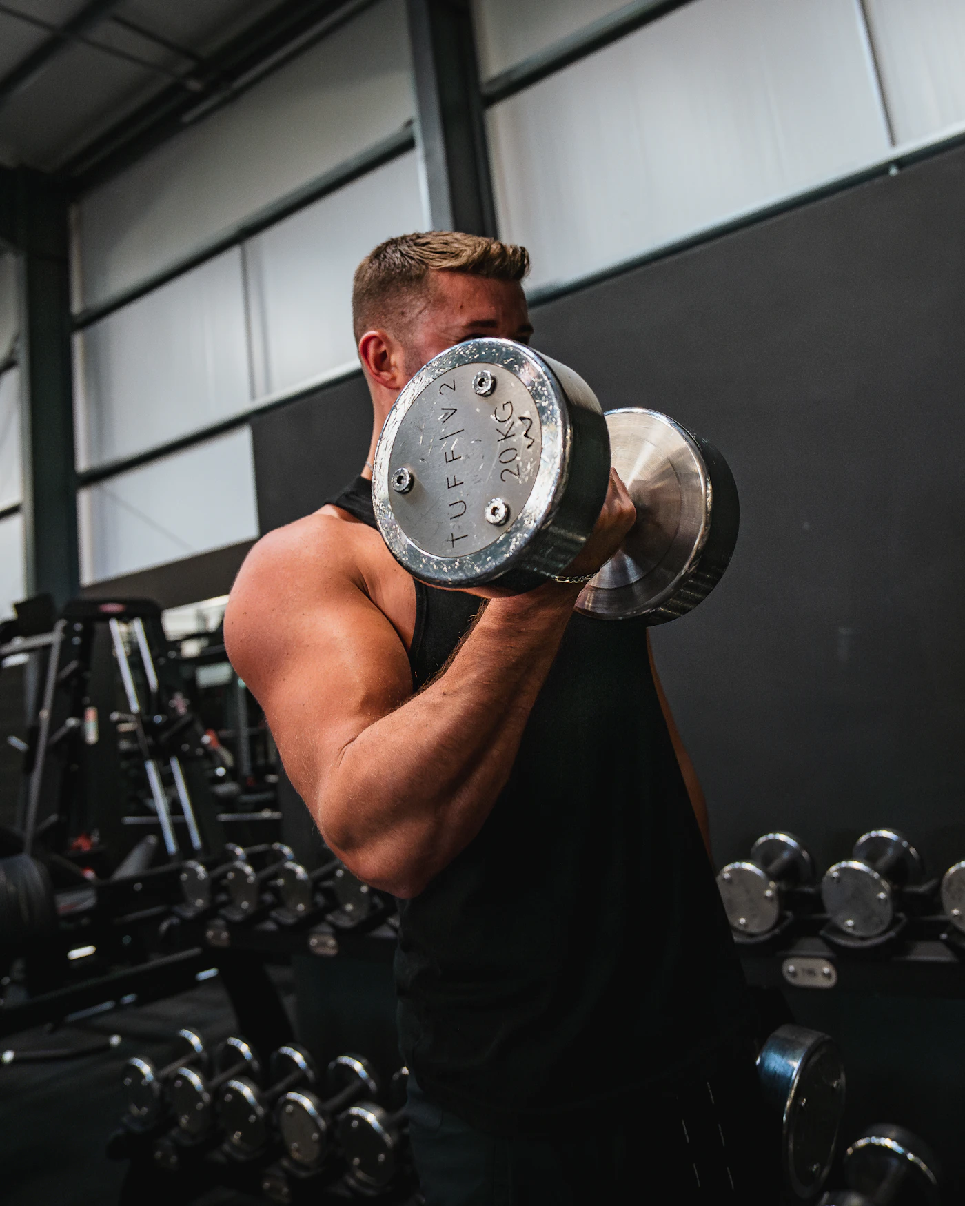 Ein muskulöser Sportler trainiert im Fitnessstudio mit Kurzhanteln.