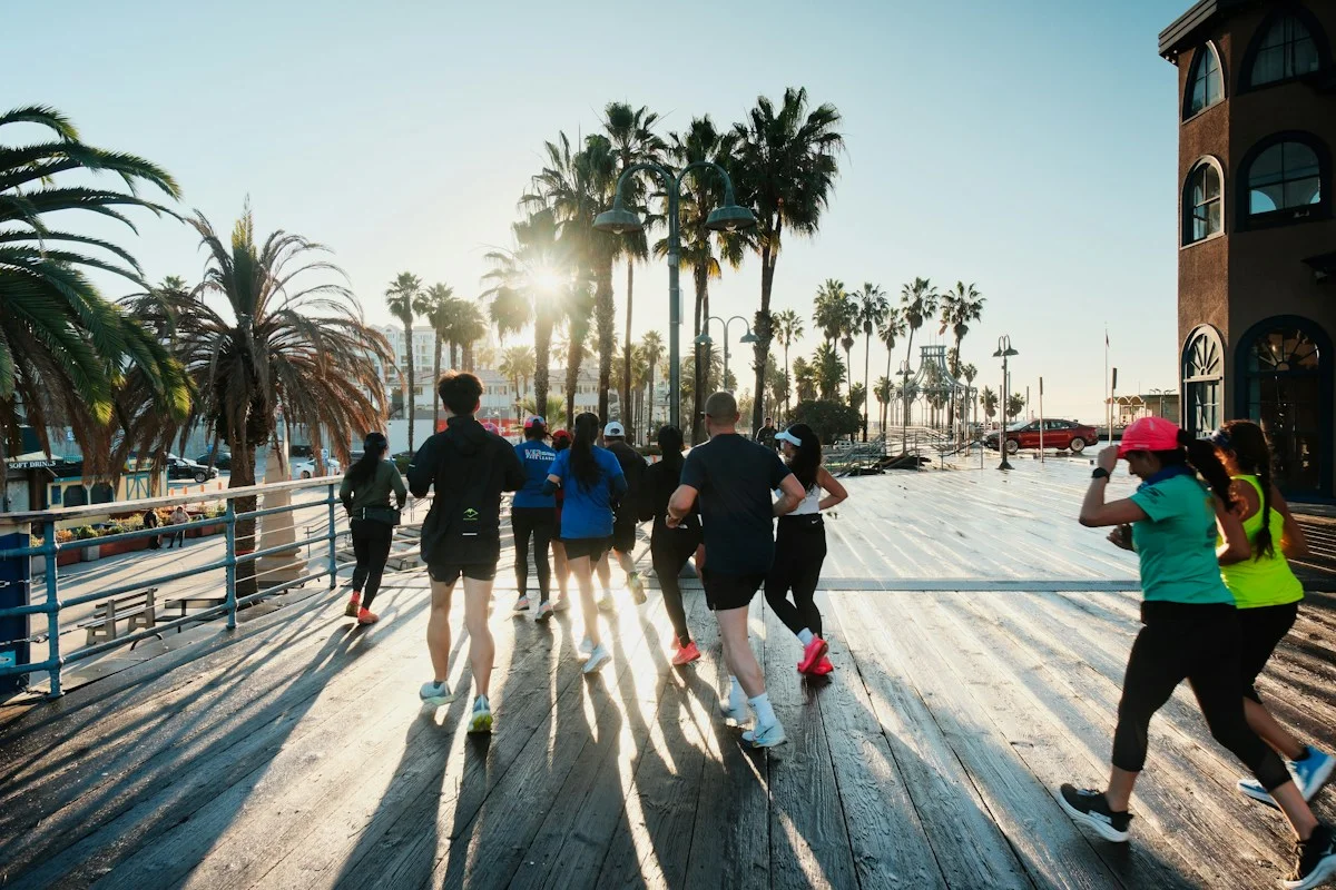 Eine Laufgruppe auf einer sonnigen Holzpromenade.
