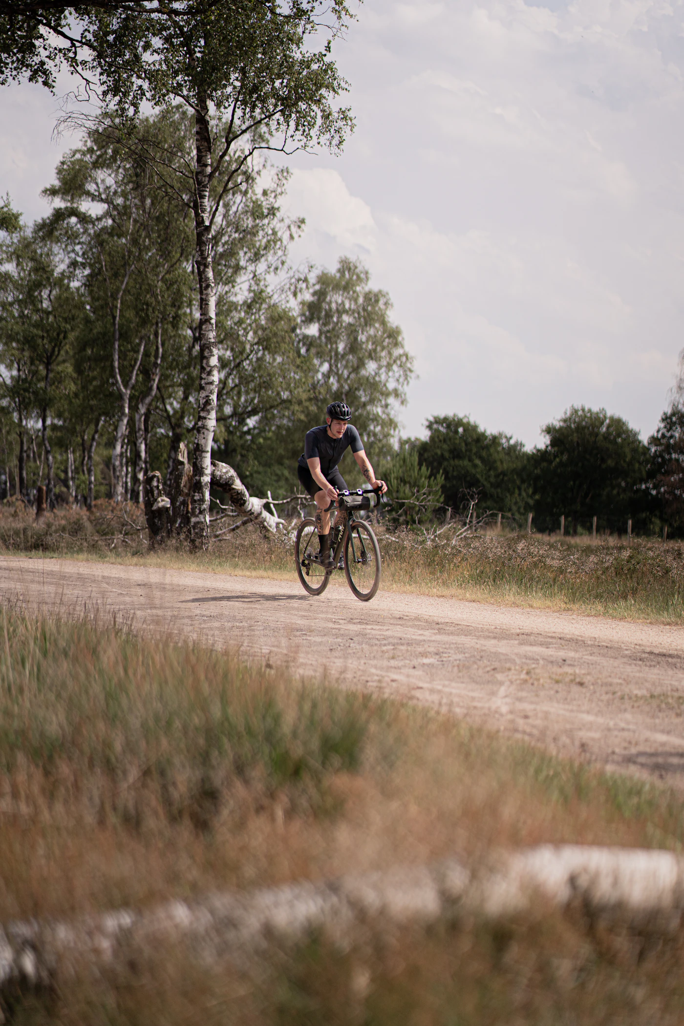 Ein Fahrradfahrer mit Helm auf einem Naturweg zwischen Bäumen.